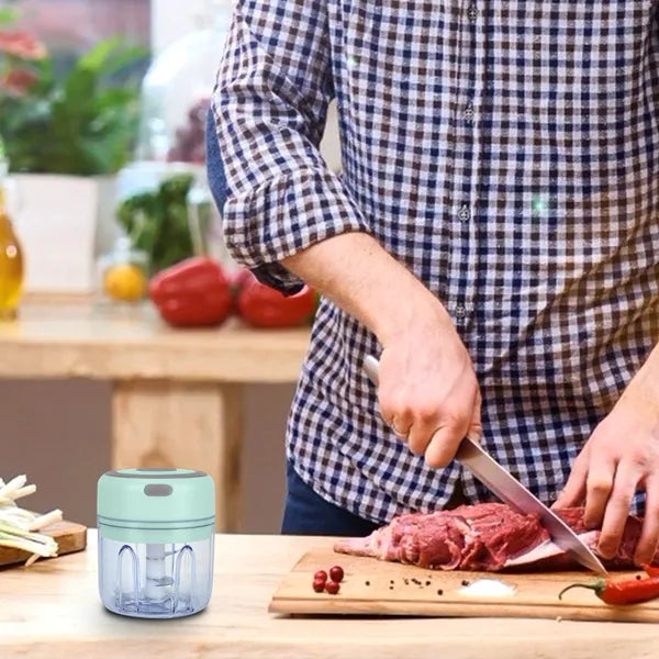 Person cutting meat on a wooden board with a small blue and gray device on the table.